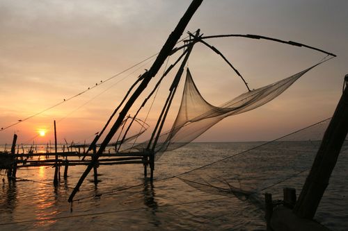 India, Kerala, Kochin, Chinese fishing nets hanging above sea at sunset